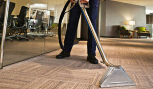 A worker vacuums up the carpeted floor of a room at this business.