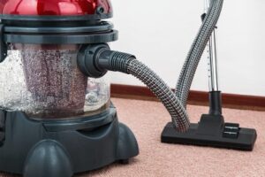 A vacuum that handles steam cleaning is used to clean a rug.